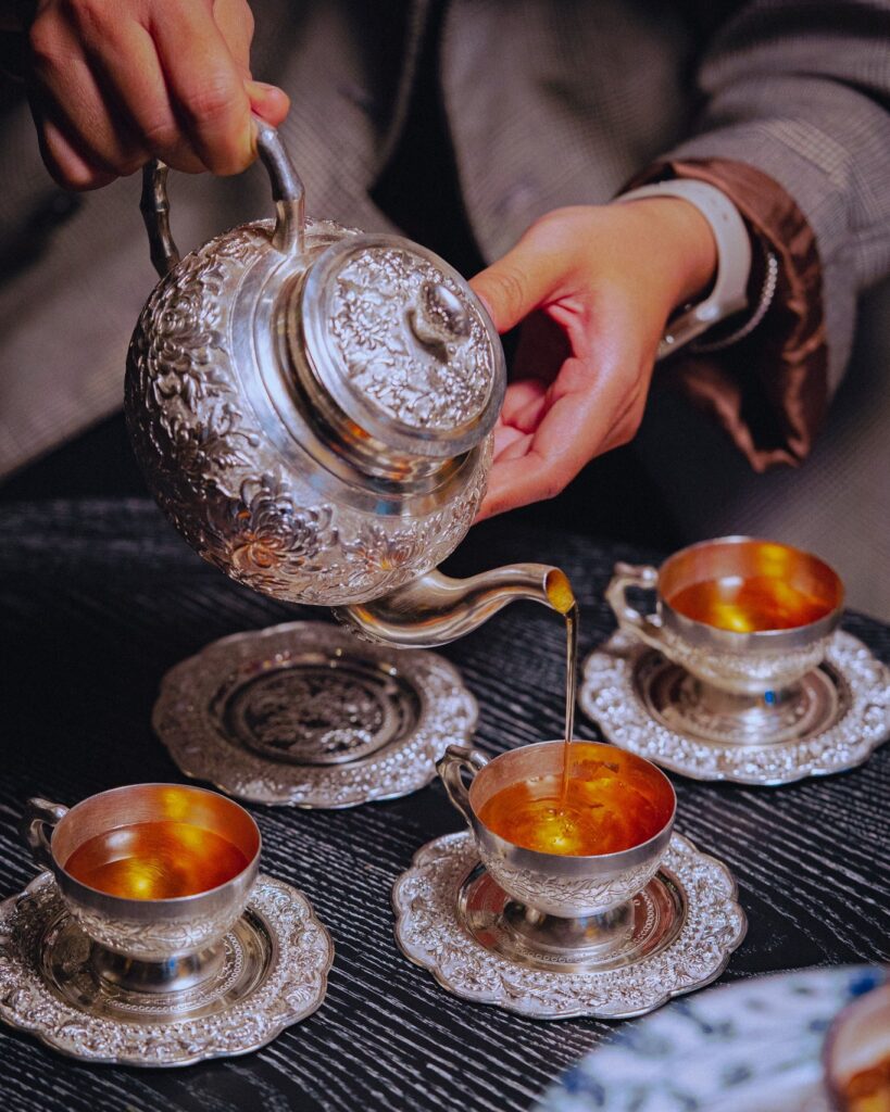 ảnh đang rót trà từ ấm bạc ra chén của Hi' de maison