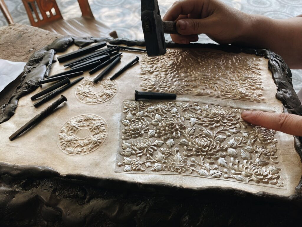 ảnh nghệ nhân đang chạm hoa văn lên thân ấm bạc trong xưởng Hi’de Maison